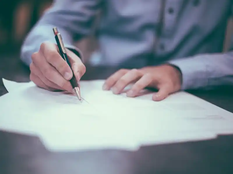 Profissional a assinar documentos de empresa com a sua marca